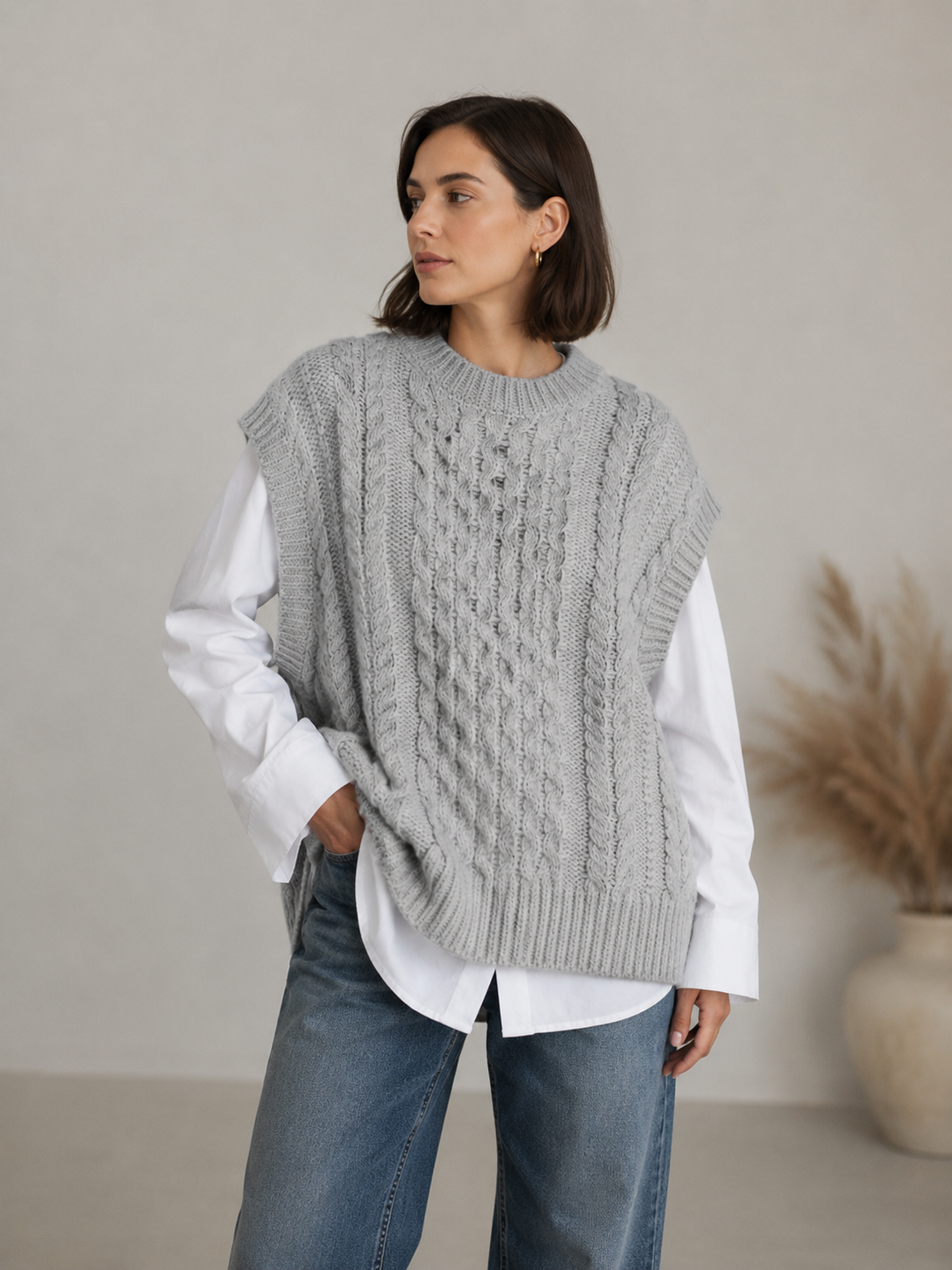 Women's cable knit vest layered over a long-sleeve top, styled for autumn and winter