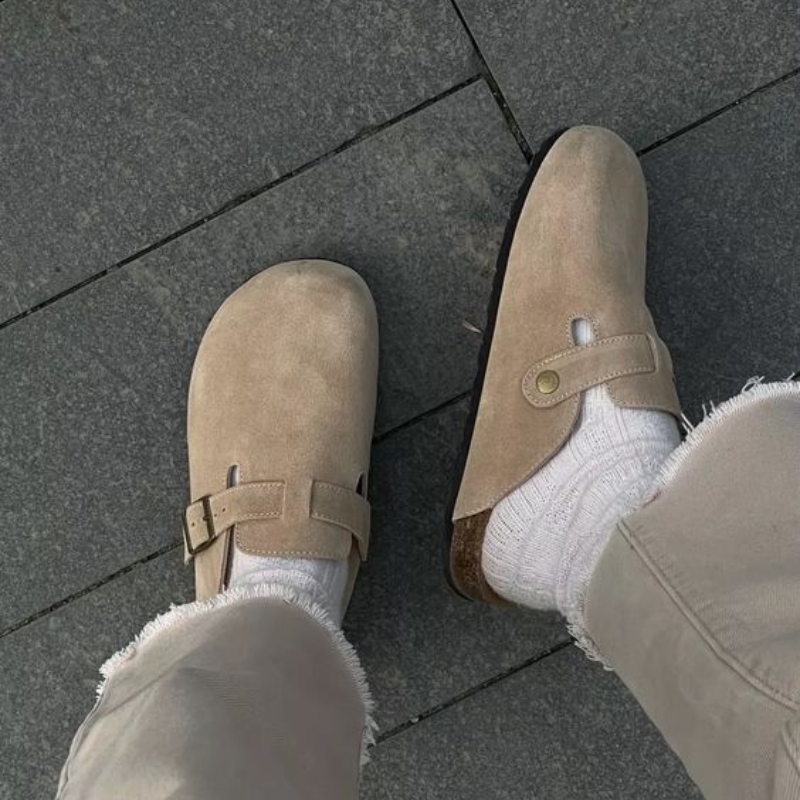 Closed-toe suede slip-on slippers with adjustable strap and stitched upper