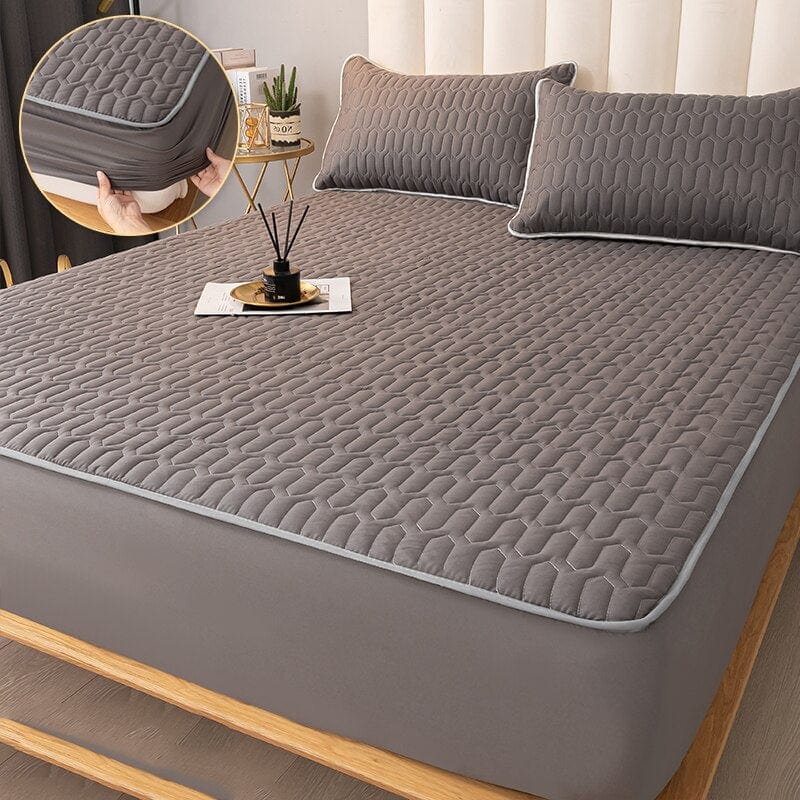 Quilted mattress protector on a single bed showing fitted sheet-style fit