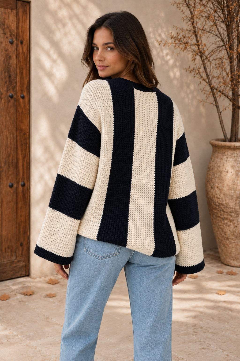 Women's cream and black striped chunky-knit sweater with wide horizontal-striped sleeves and black ribbed cuffs, back view