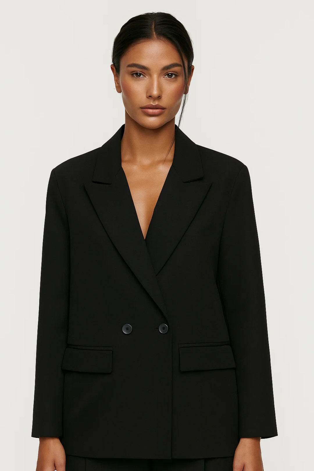 Women's tailored blazer with double-breasted closure, flap pockets, and structured woven fabric