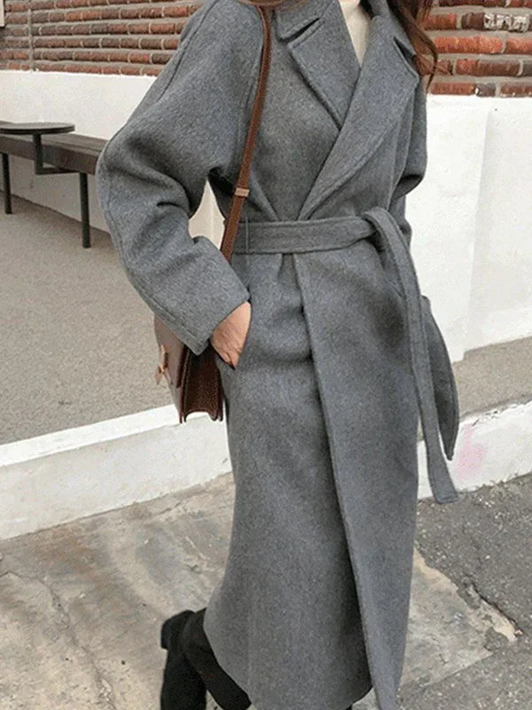 Long women's polyester coat with waist belt and lapel collar, front-facing view